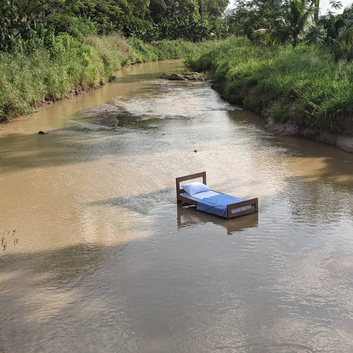 A bed stands in a river.