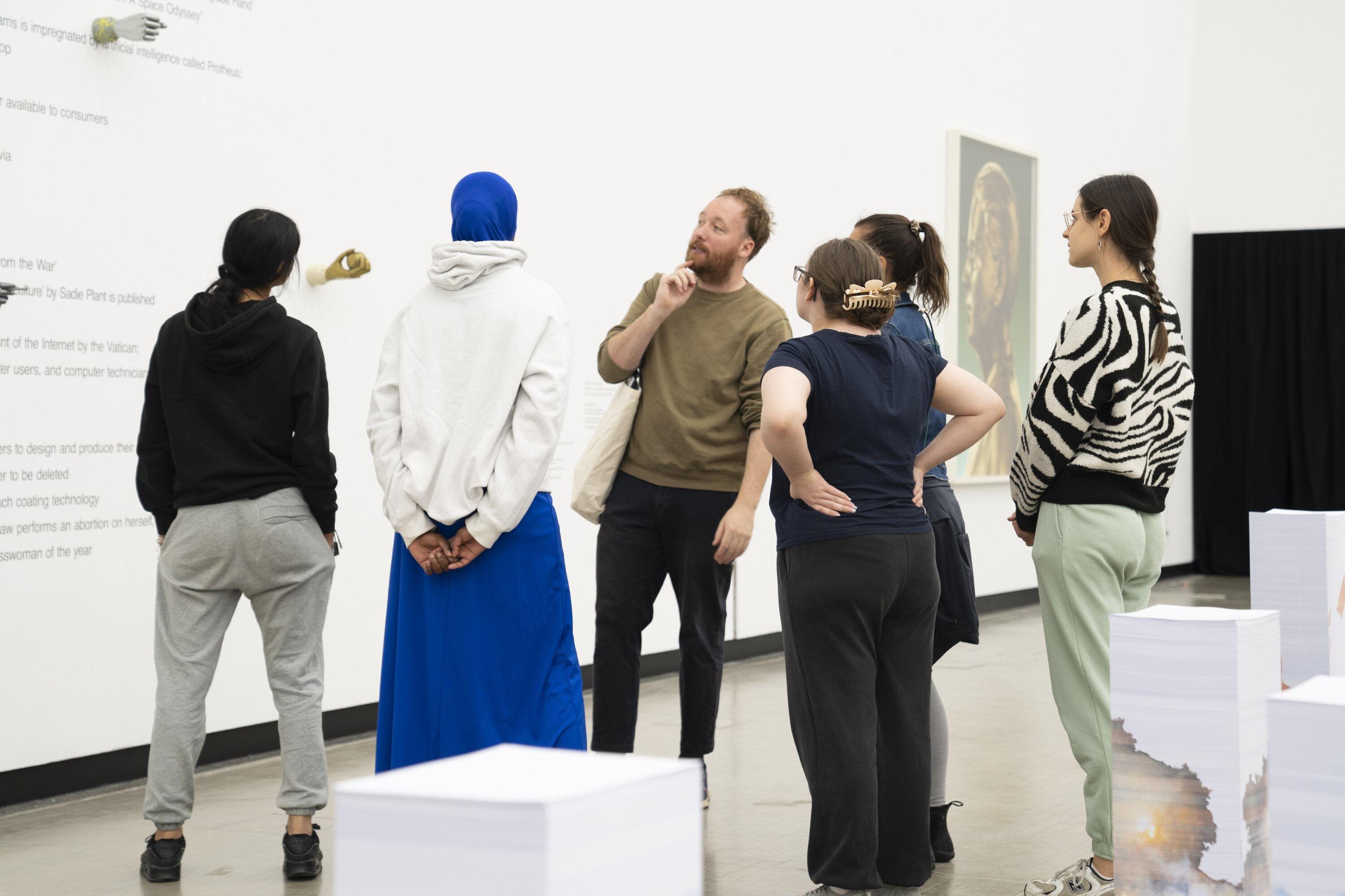Eine Gruppe betrachtet Kunstwerke von Aleksandra Domanović.