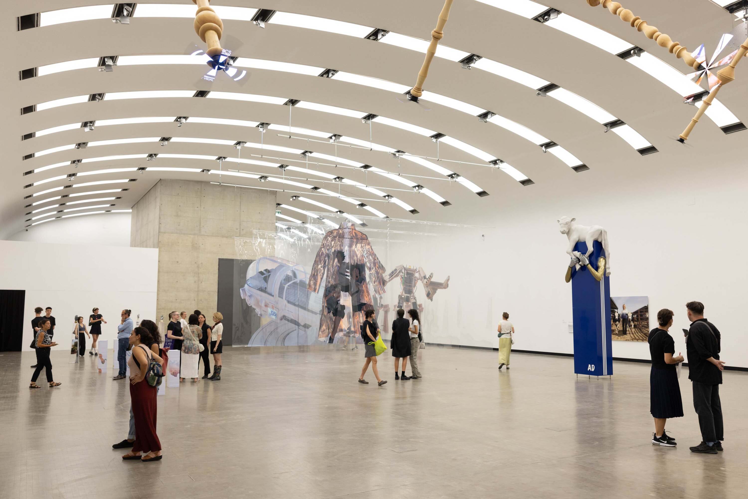 Mehrere Personen stehen in einer gro&szlig;en Halle mit Kunstwerken von Aleksandra Domanović.