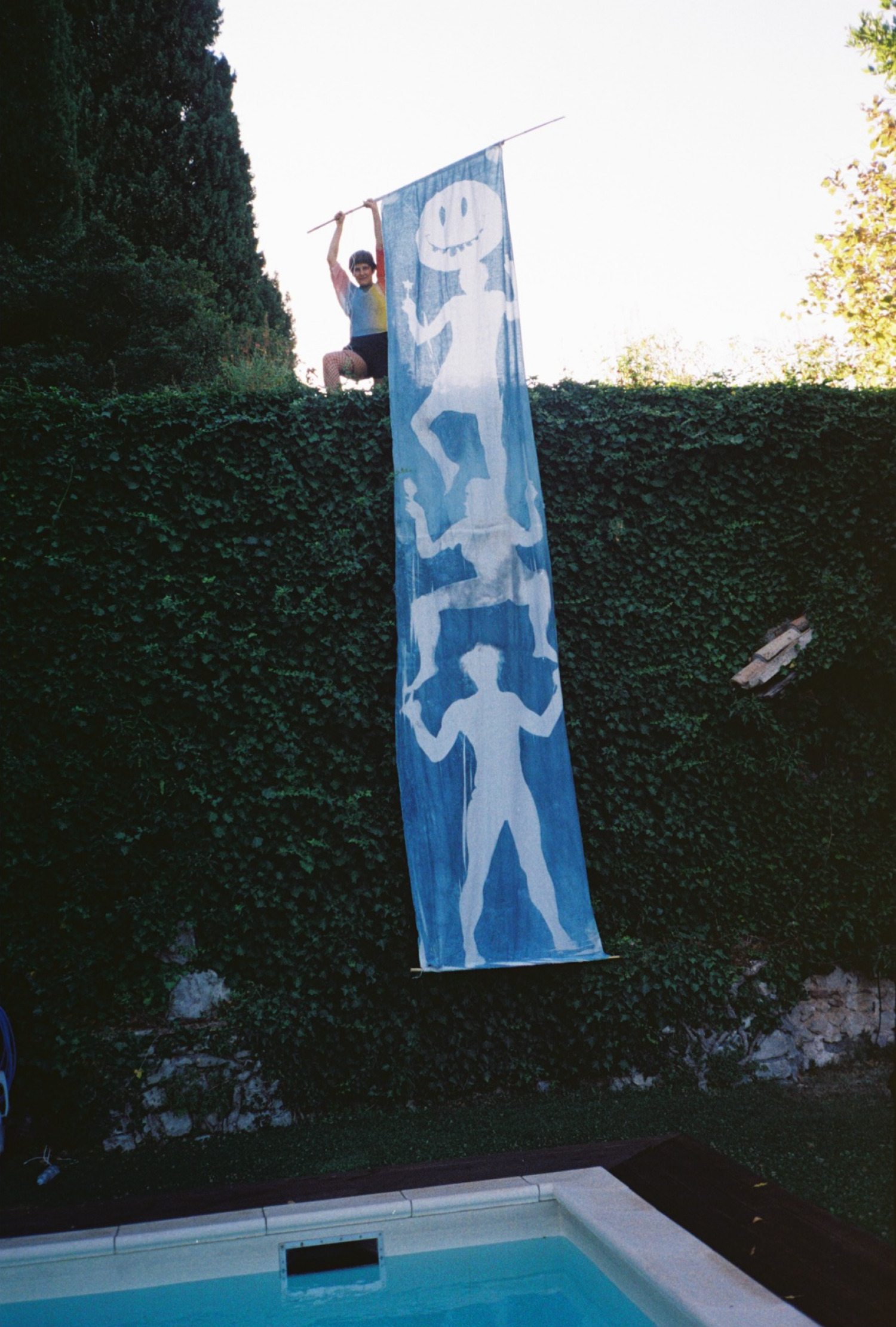 Eine Frau h&auml;lt eine Fahne mit Figuren &uuml;ber einen Pool