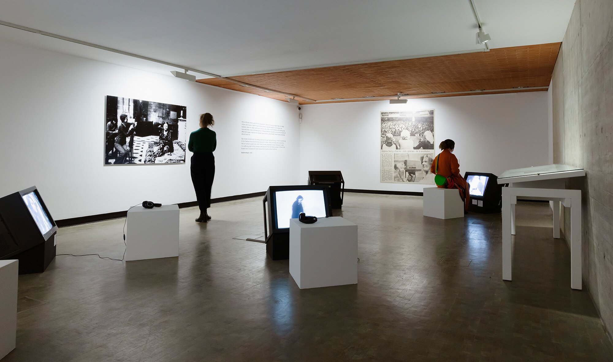 Ausstellungsansicht mit Fernsehern und Wandtexten
