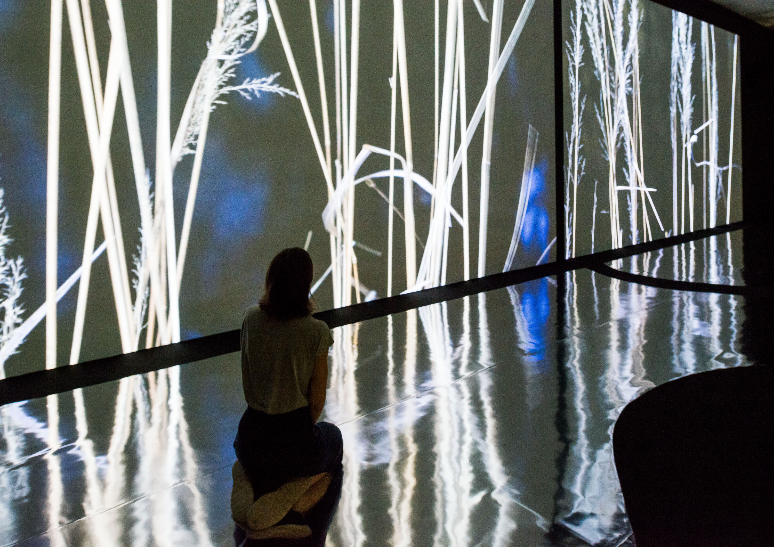 Ausstellungsansicht mit kniender Person vor Filmprojektion