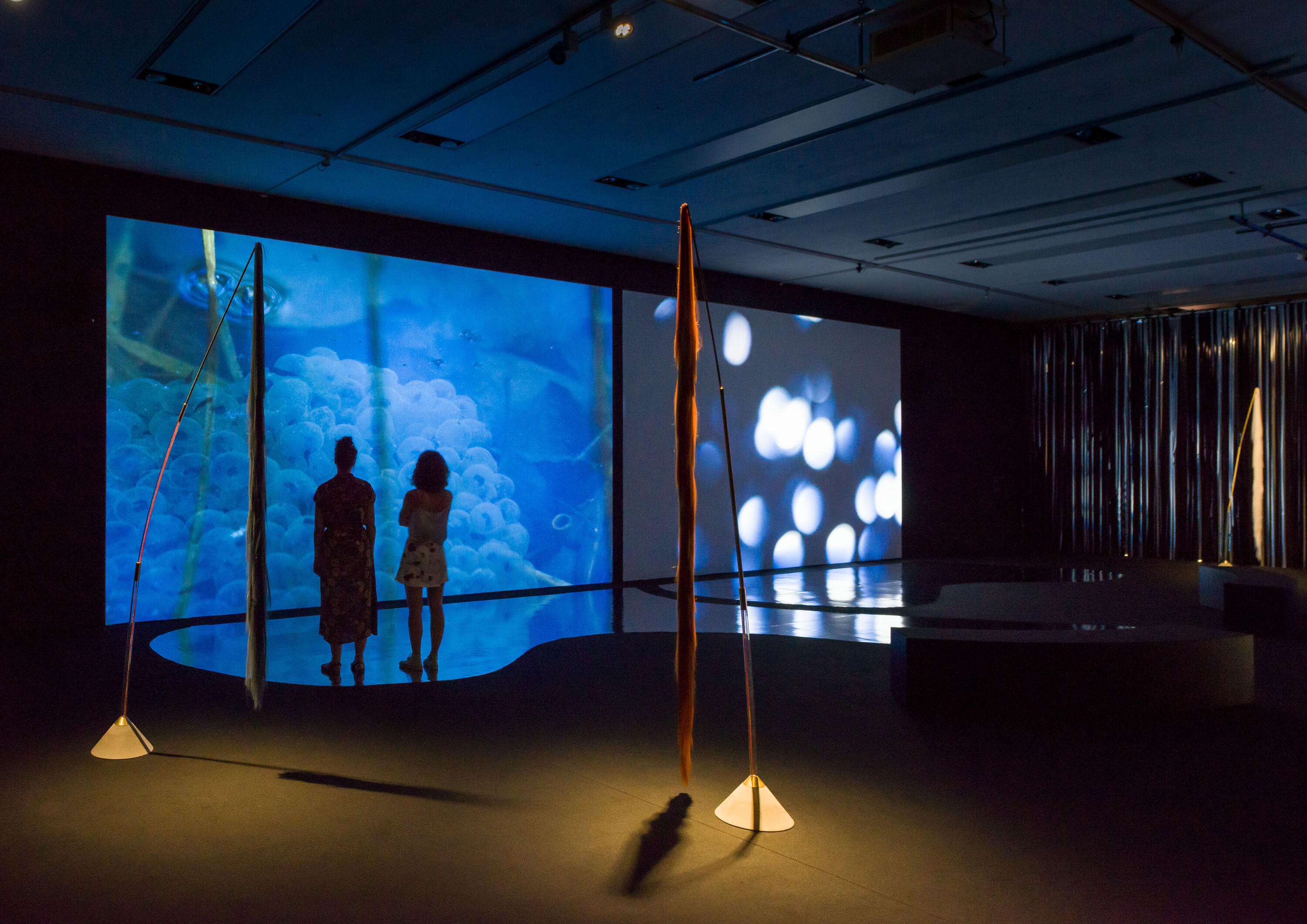 Ausstellungsansicht mit Skulpturen und Filmprojektionen