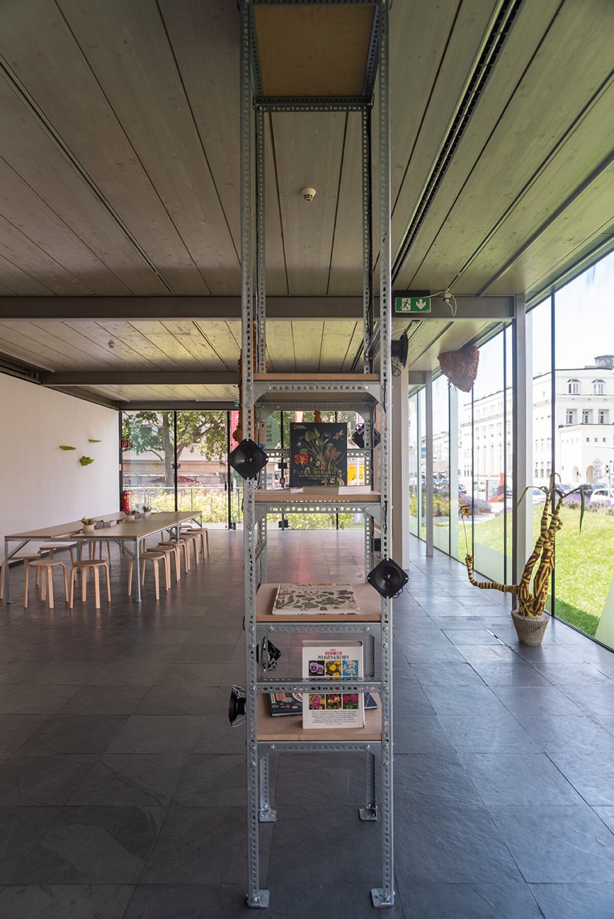 Ausstellungsansicht mit Regal und Tisch mit St&uuml;hlen