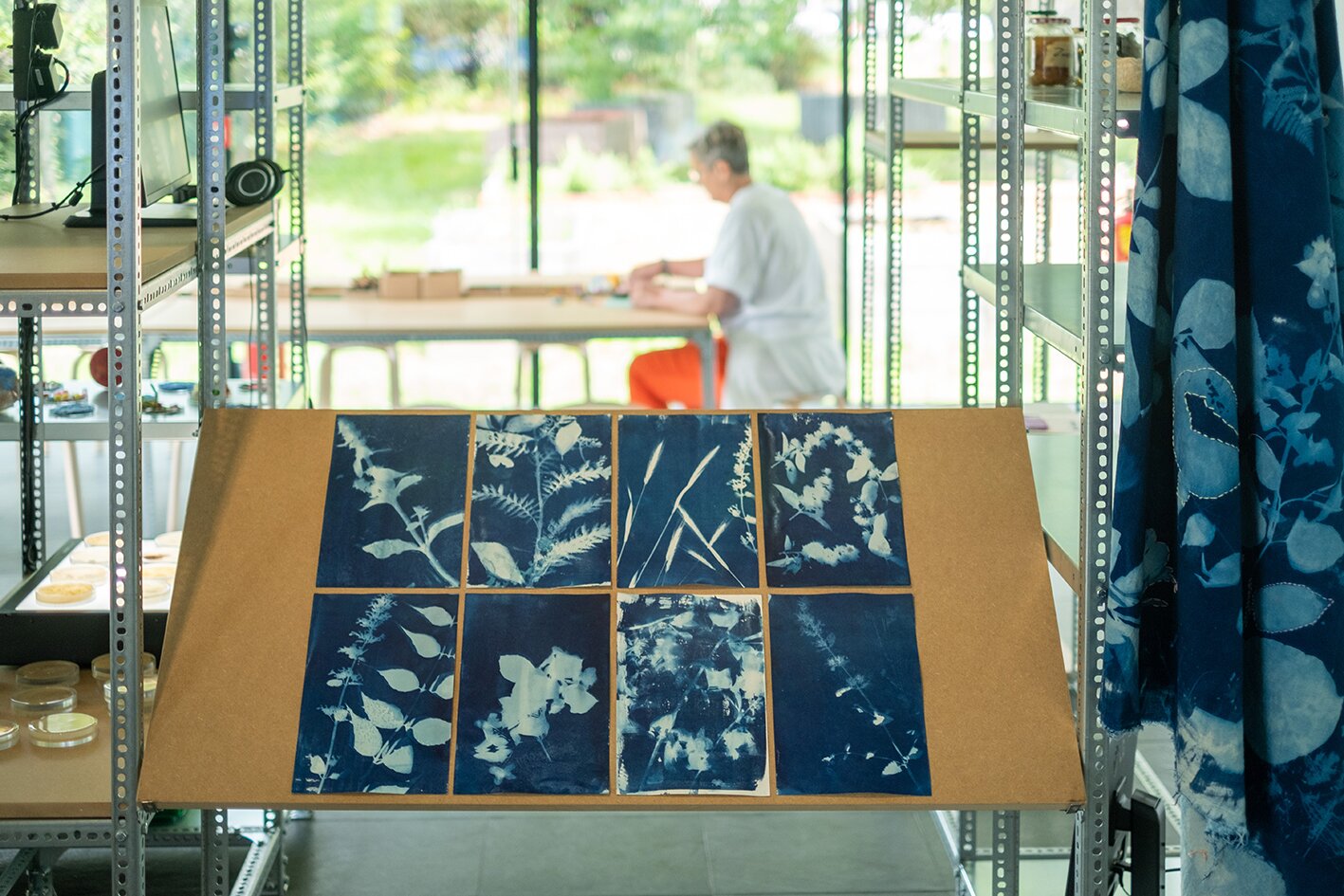 Ausstellungsansicht, im Vordergrund mit Pflanzenmustern bedruckte Stoffe
