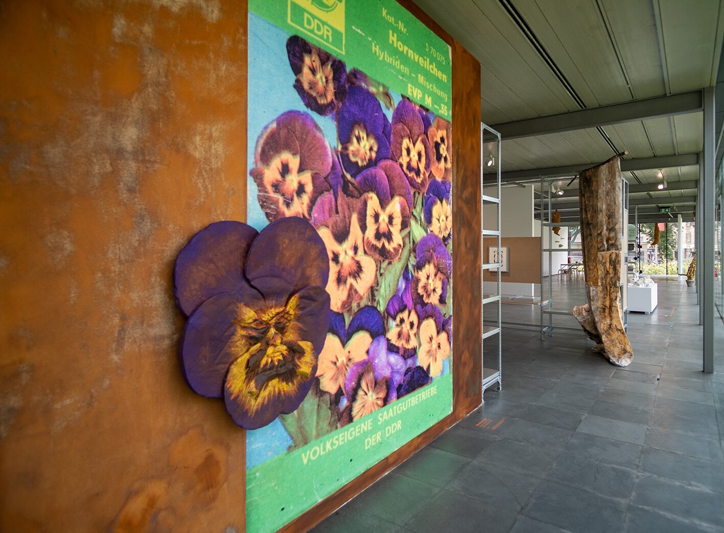 Ausstellungsansicht mit großem Blumenplakat und Text: Volkseigene Saatgutbetriebe der DDR