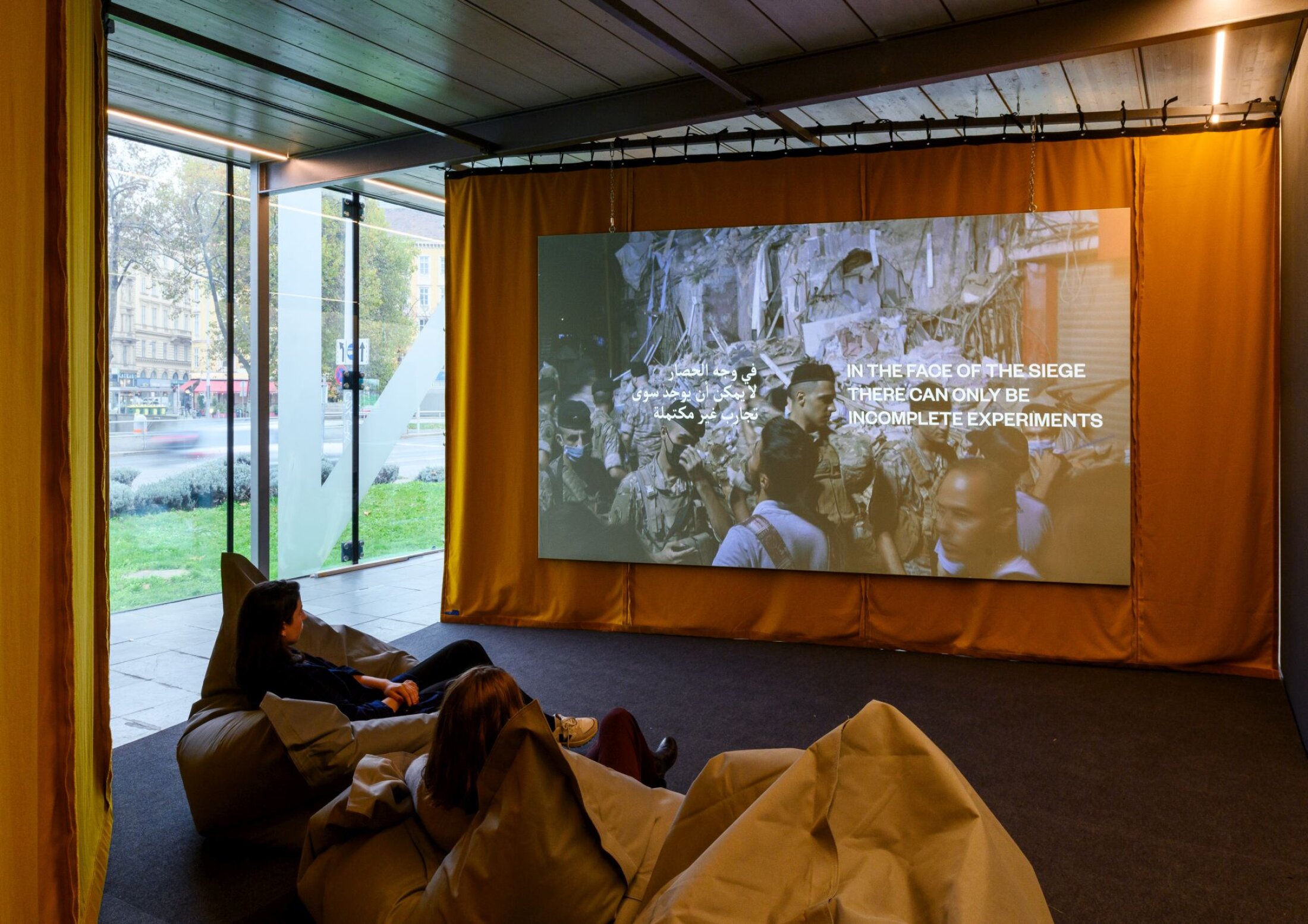 Der Film von Bassem Saad wird auf einer Leinwand vor einem orangen Vorhang pr&auml;sentiert.