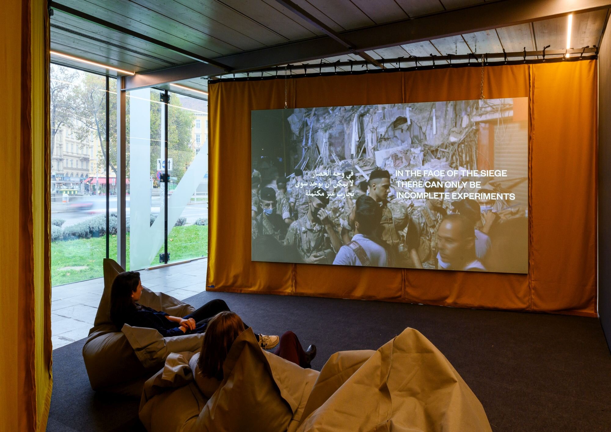 Der Film von Bassem Saad wird auf einer Leinwand vor einem orangen Vorhang präsentiert.