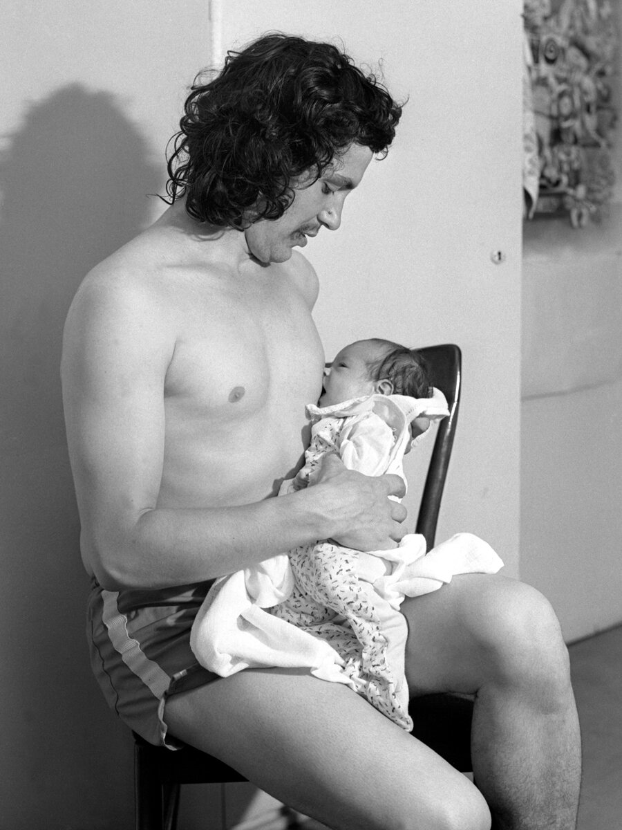 Schwarz-wei&szlig; Foto eines Mannes mit Baby an der Brust.