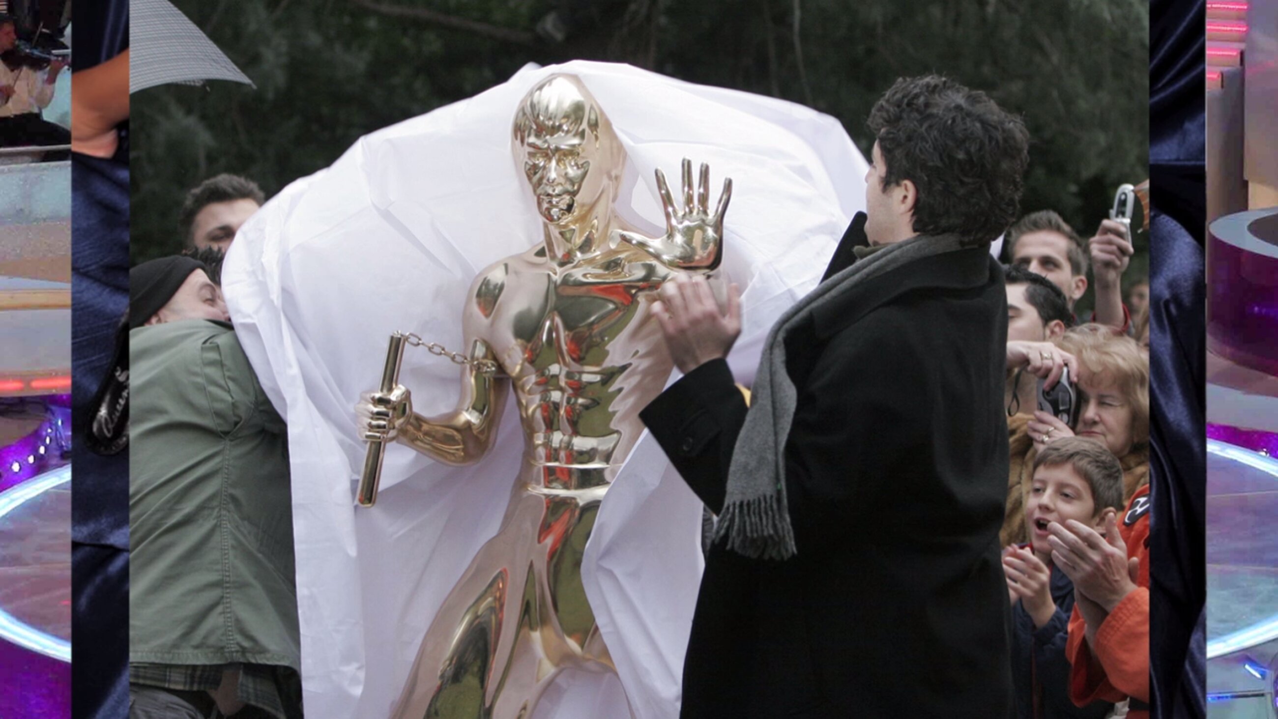 Filmstill mit einem goldenen Roboter, der von Menschen umgeben ist.