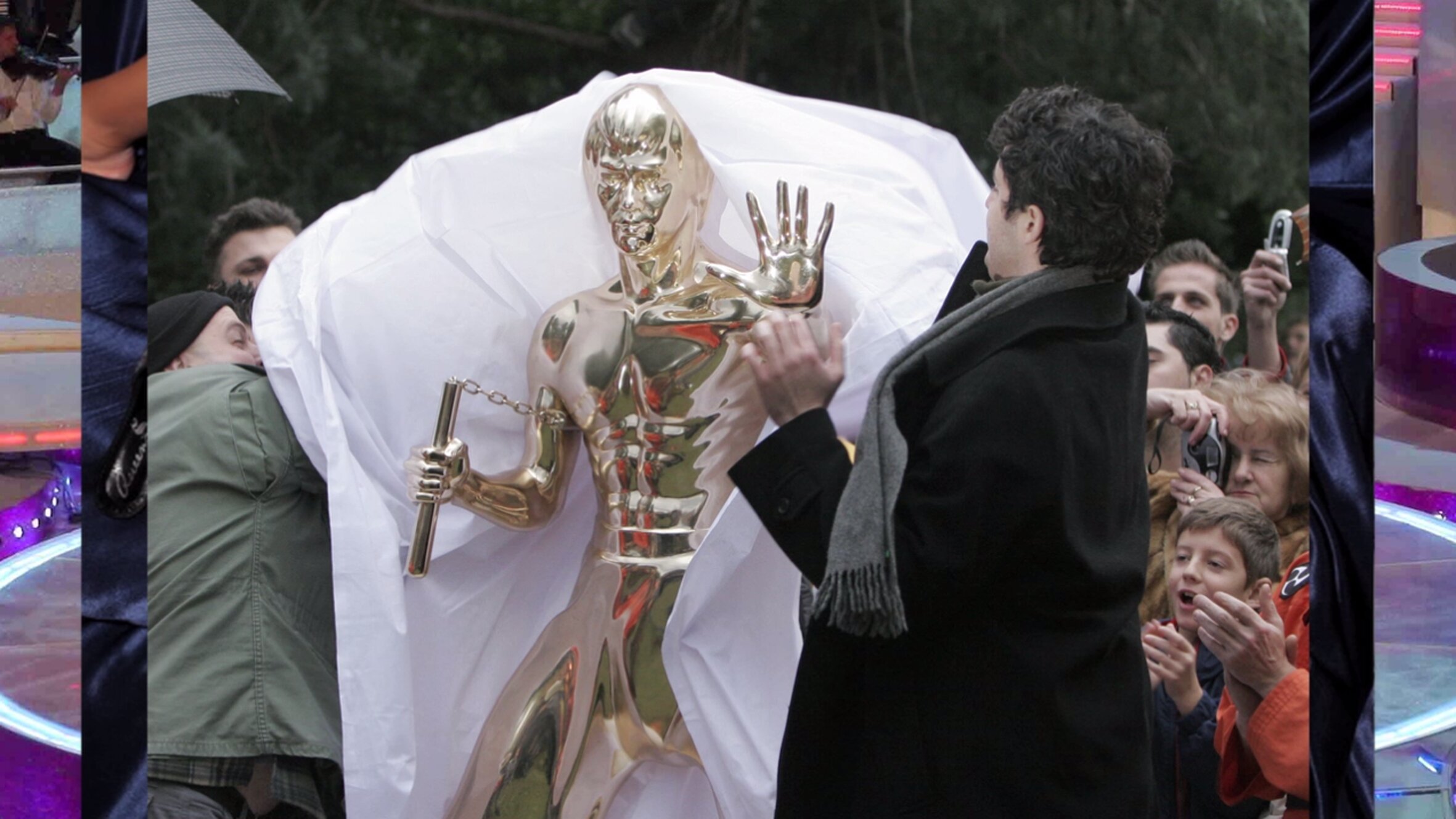 Filmstill mit einem goldenen Roboter, der von Menschen umgeben ist.